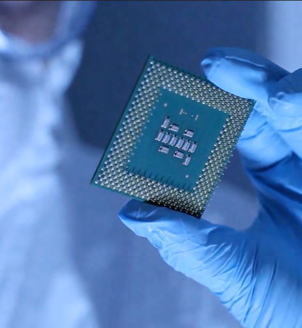 A gloved hand holding a semiconductor chip